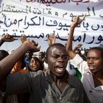 Wütende Demonstranten vor der Universität Zalingei in West Darfur/Sudan mit erhobenen Fäusten und einem großen Transparent im Dezember 2010.