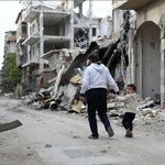 Ein Junge hält die Hand seines Vater in der zerstörten syrischen Stadt Homs