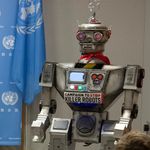 Vor einem Banner mit UN-Logo steht ein Roboter. An seiner Brust haftet ein Schild mit der Aufschrift: Stop Killer Robots