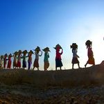 Eine Gruppe von Frauen des Globalen Südens trägt Gegenstände auf ihren Köpfen.