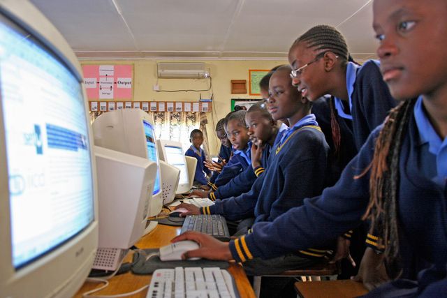 Schülerinnen und Schüler arbeiten gemeinsam an Computern. 
